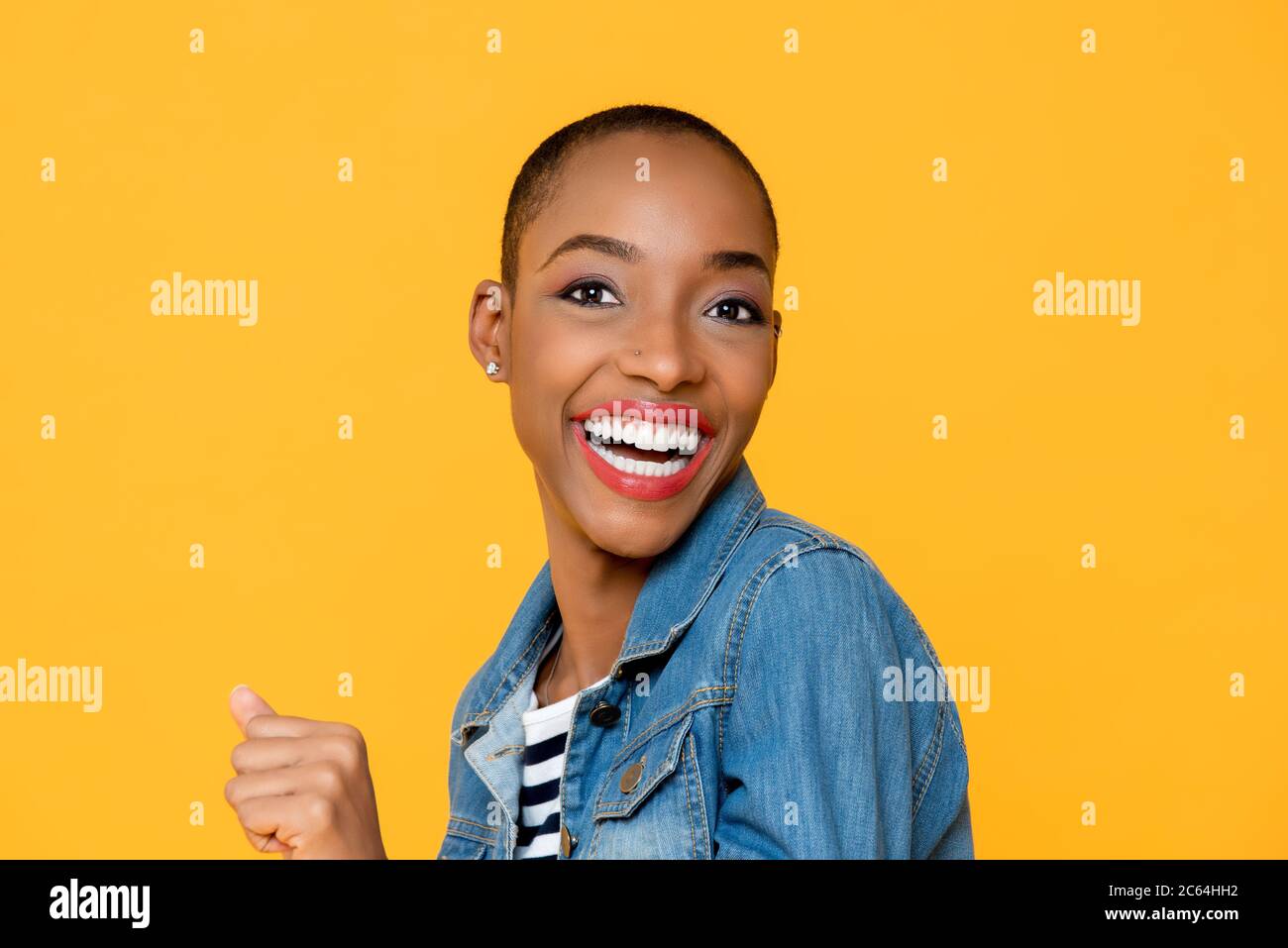 Primo piano ritratto di allegra ed eccitata sorridente giovane afroamericana con pugno accanito in uno sfondo giallo isolato studio Foto Stock