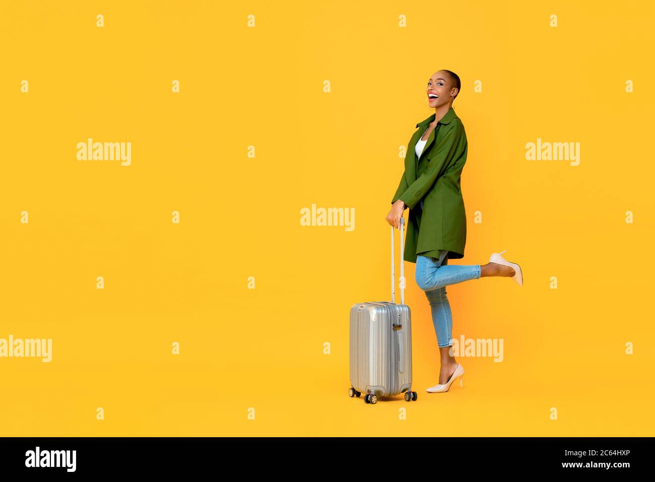 Ritratto a lunghezza intera di giovane entusiasta turista afroamericano che tiene i bagagli su una gamba sollevata in piedi gesto pronto a viaggiare in strada isolata Foto Stock