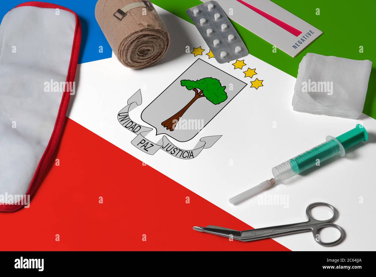 Bandiera della Guinea Equatoriale con kit medico di primo soccorso su sfondo di tavola di legno. Concetto nazionale del sistema sanitario, tema medico. Foto Stock