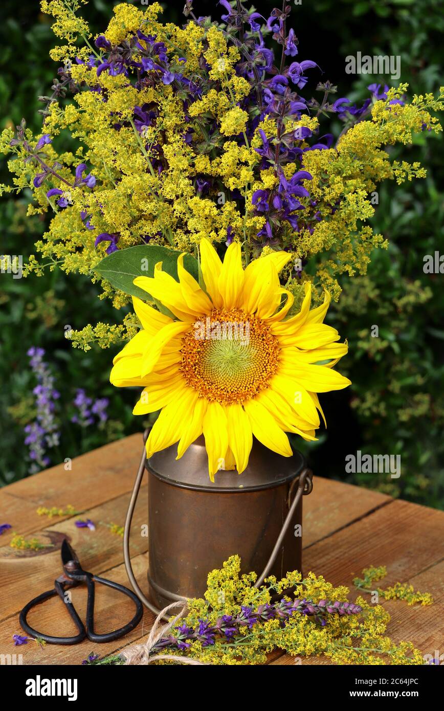 bouquet con fiore del sole e fiori di prato in giallo e viola in lattina di latte d'annata Foto Stock