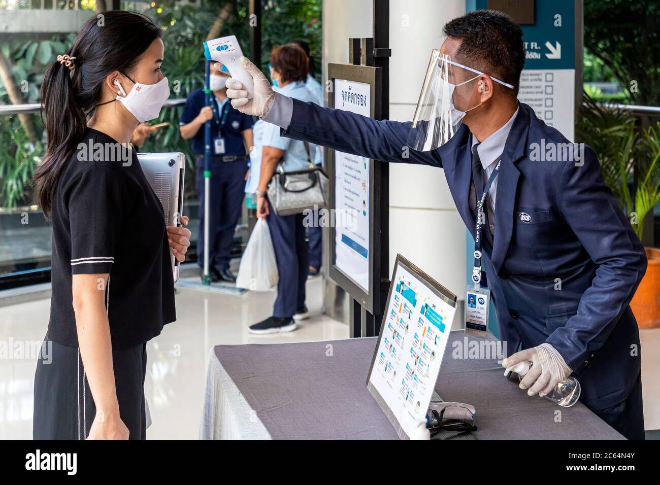 Guardia di sicurezza che controlla la temperatura del pubblico all'ingresso del centro commerciale durante la pandemia covid 19, Bangkok, Thailandia Foto Stock