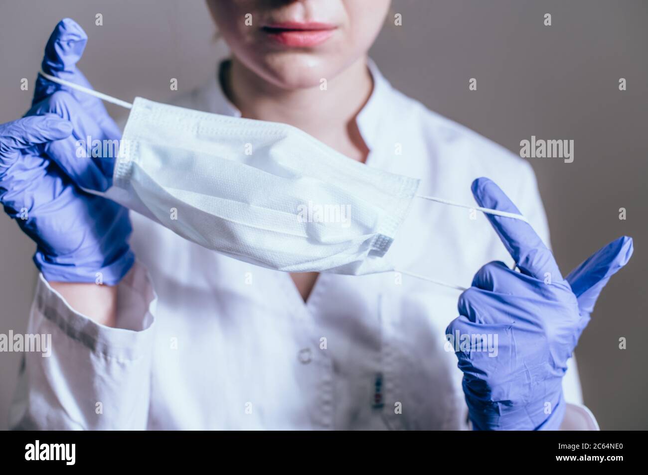 Donna medico in un cappotto bianco indossa una maschera protettiva per il lavoro Foto Stock