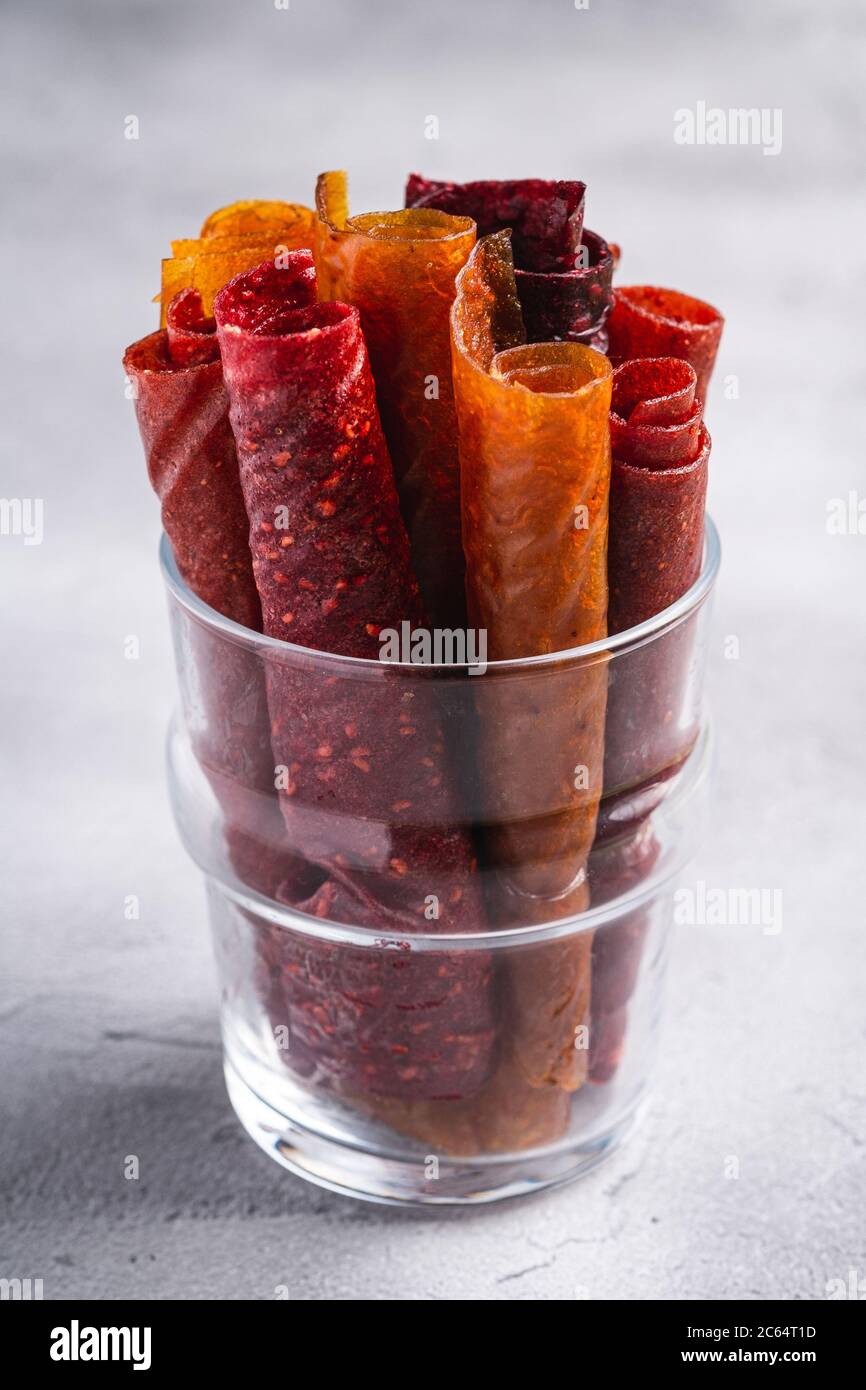 Pastiglia di frutta in tazza di vetro su fondo di pietra cemento. Alimenti biologici senza zucchero, preparati con lampone, fragola, pesca e mela. Casa vegana Foto Stock