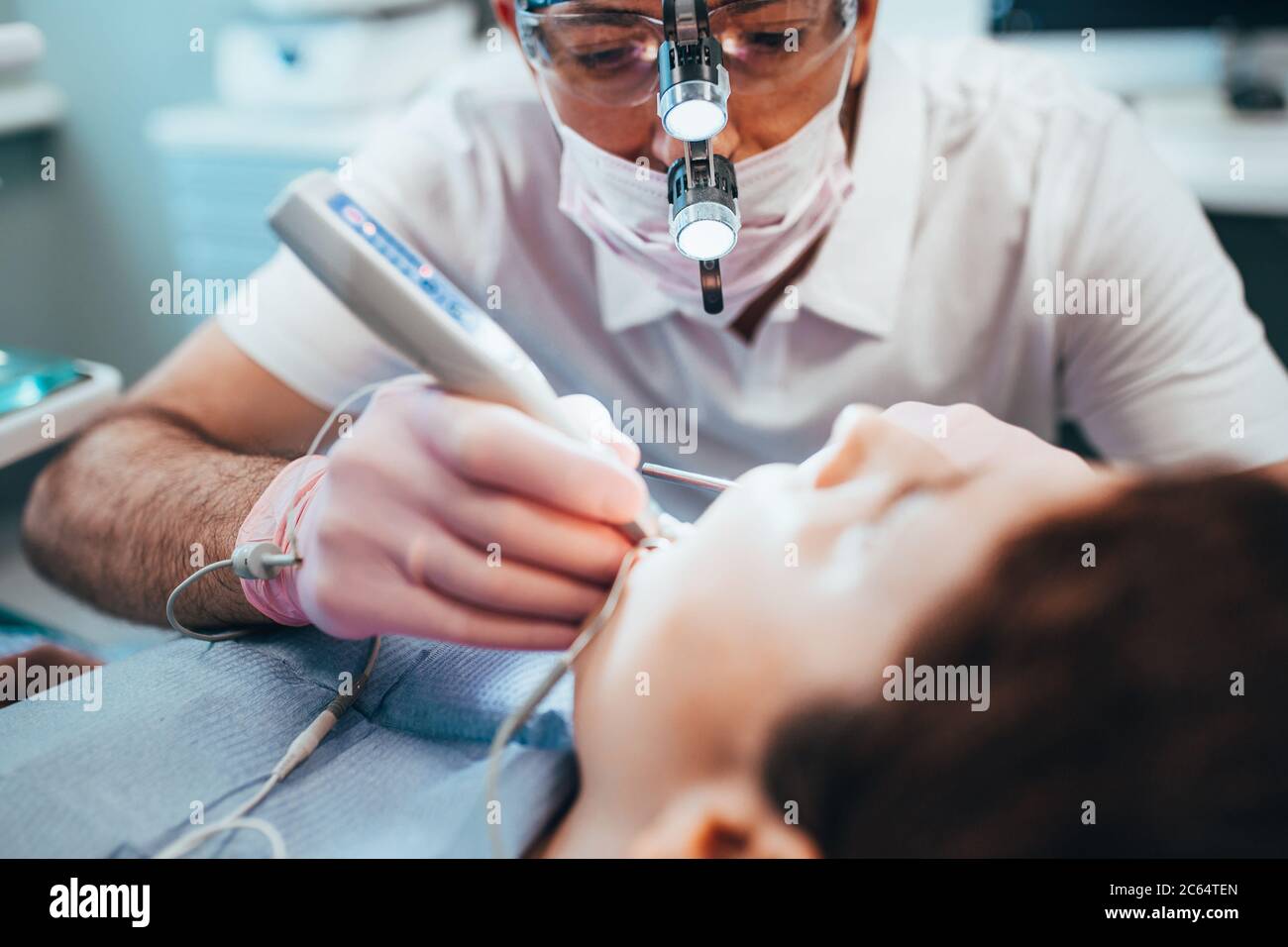 Un dentista al lavoro utilizza una luce LED locale - l'effetto della radiazione ultravioletta su un riempimento dentale Foto Stock