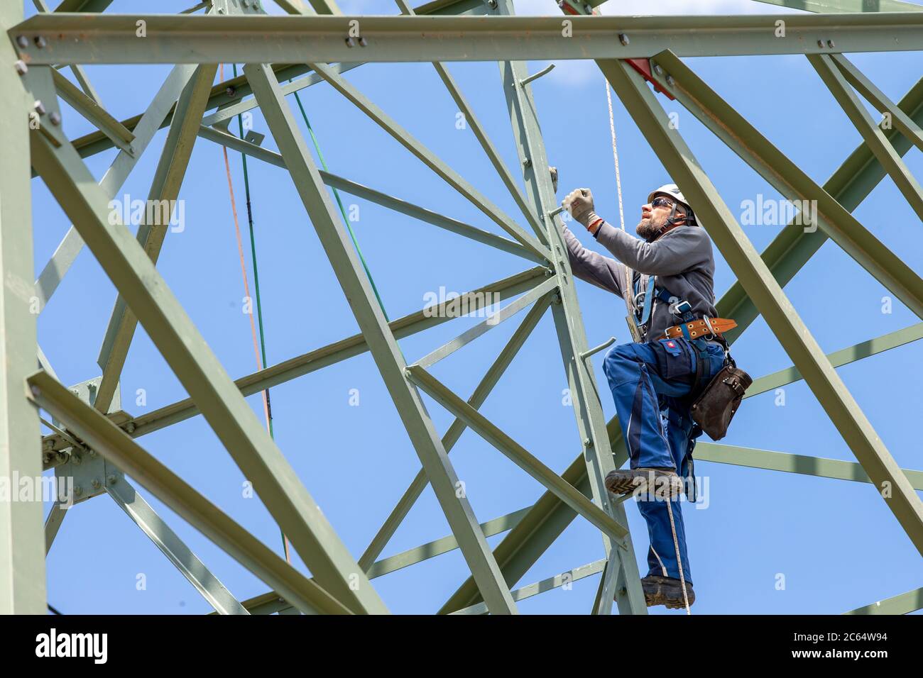 Heidenau, Germania. 06 luglio 2020. Un tecnico sale sul polo di potenza fino al suo posto di lavoro. A Heidenau, vicino a Dresda, in Sassonia, è in corso la costruzione di una nuova linea elettrica con tralicci elettrici più potenti per il trasporto di energia elettrica tra la Germania settentrionale e quella meridionale. Registrato in una riunione stampa con l'operatore di rete 50 Hertz. Credit: Daniel Schäfer/dpa-Zentralbild/ZB/dpa/Alamy Live News Foto Stock