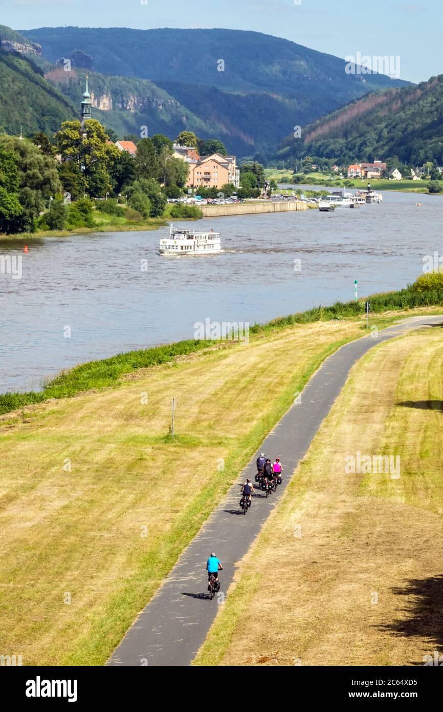 La gente pedalando su una pista ciclabile che conduce attraverso una valle lungo il fiume Elba Sassonia Germania Foto Stock