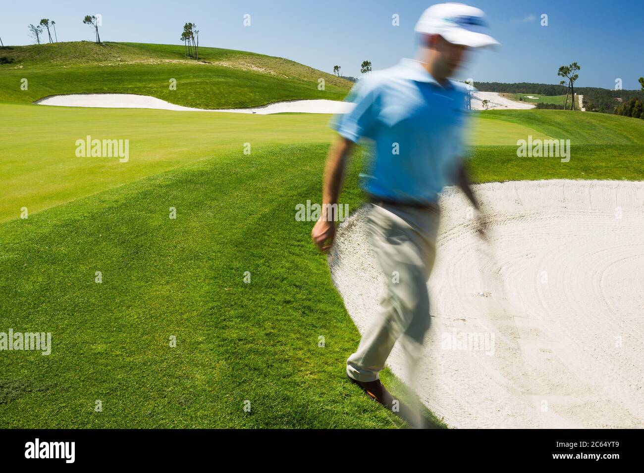 Golfer maschio che cammina nella trappola di sabbia. Foto Stock