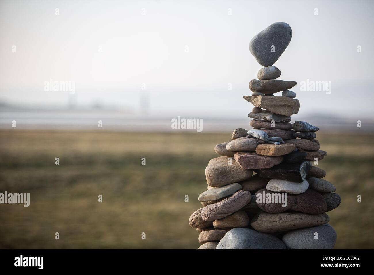 Una torre di pietre di varie dimensioni accatastate in un cairn, la pietra superiore che bilancia su un punto. Foto Stock