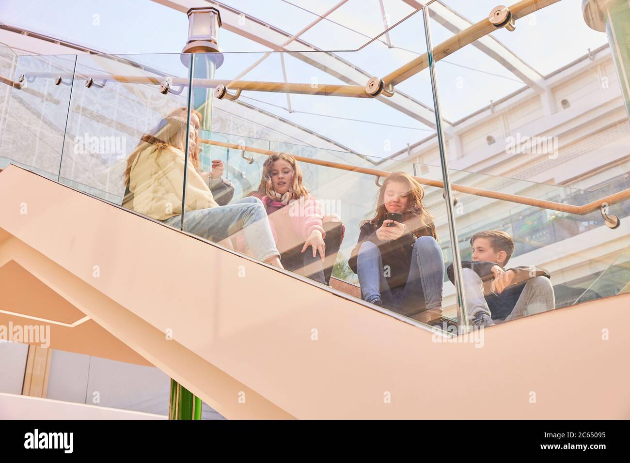 Gruppo di ragazze adolescenti seduti su una scala in un centro commerciale, chiacchierando. Foto Stock