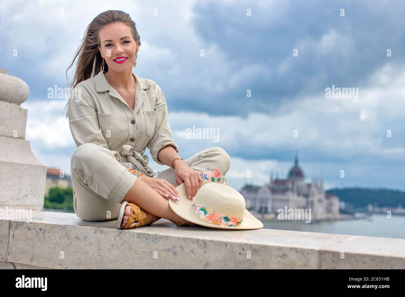 Giovane donna degli anni 20 siede su una ringhiera in marmo al Ponte Margherita, panorama di Budapest, Ungheria Foto Stock