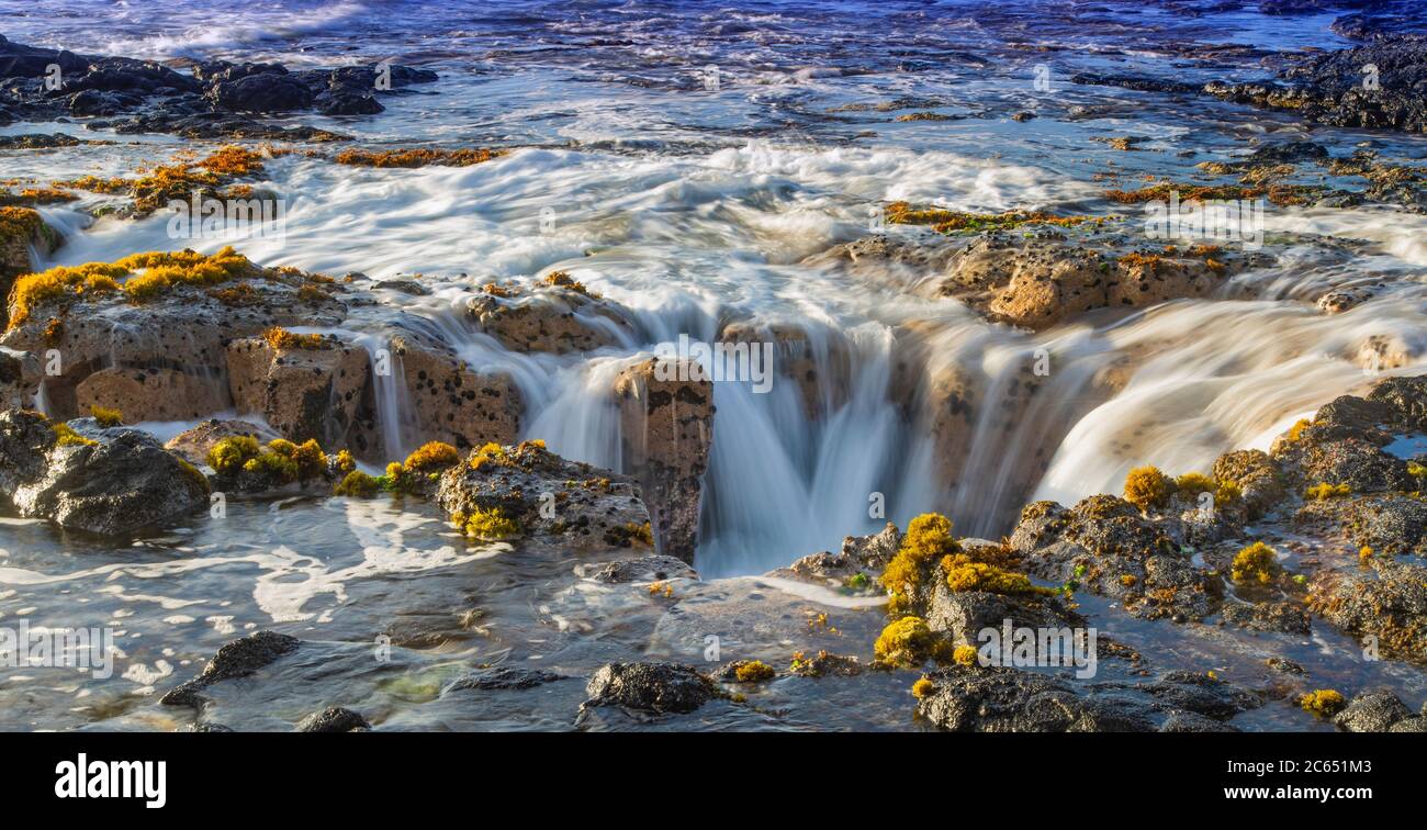 Onde oceaniche che riempia il pozzo di lava di Pele vicino a Wawaloli Beach Sulla Big Island delle Hawaii Foto Stock