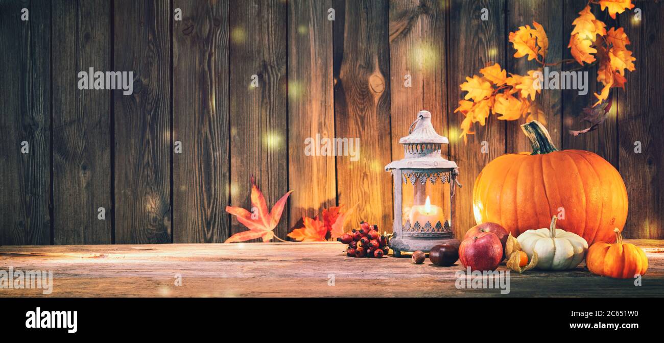 Sfondo di ringraziamento con zucche, lanterna, frutta e foglie cadenti su tavola rustica in legno Foto Stock
