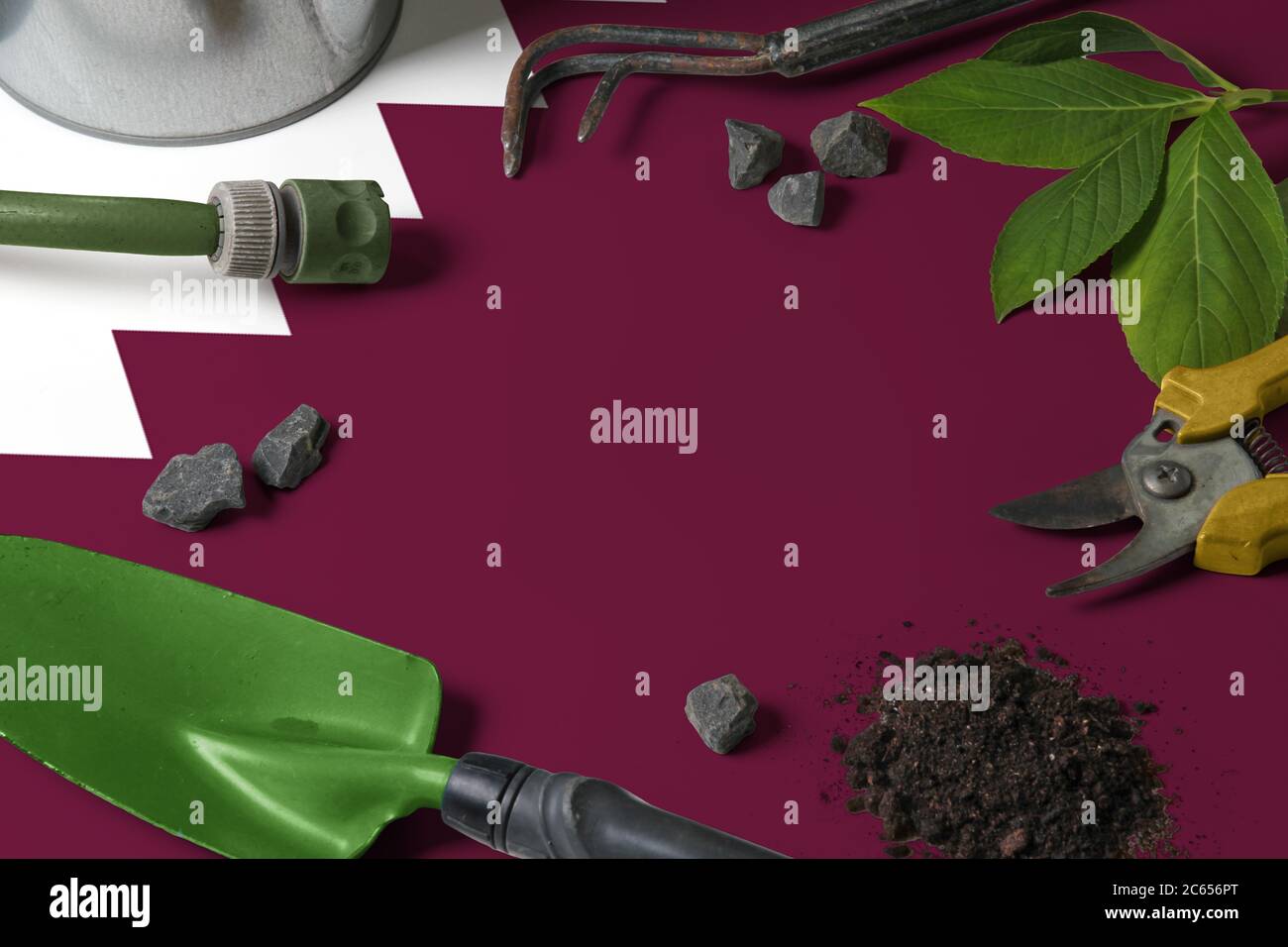 Bandiera del Qatar con gli attrezzi di giardinaggio di sfondo sul tavolo. Primavera nel giardino con spazio libero per la copia. Foto Stock