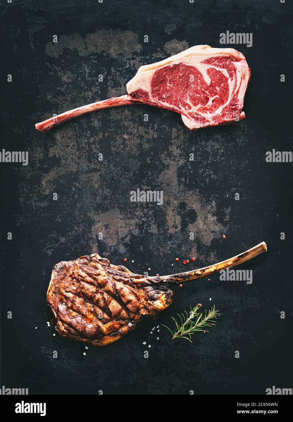Black angus Tomahawk bistecche di manzo crude e grigliate con condimento su sfondo rustico scuro Foto Stock