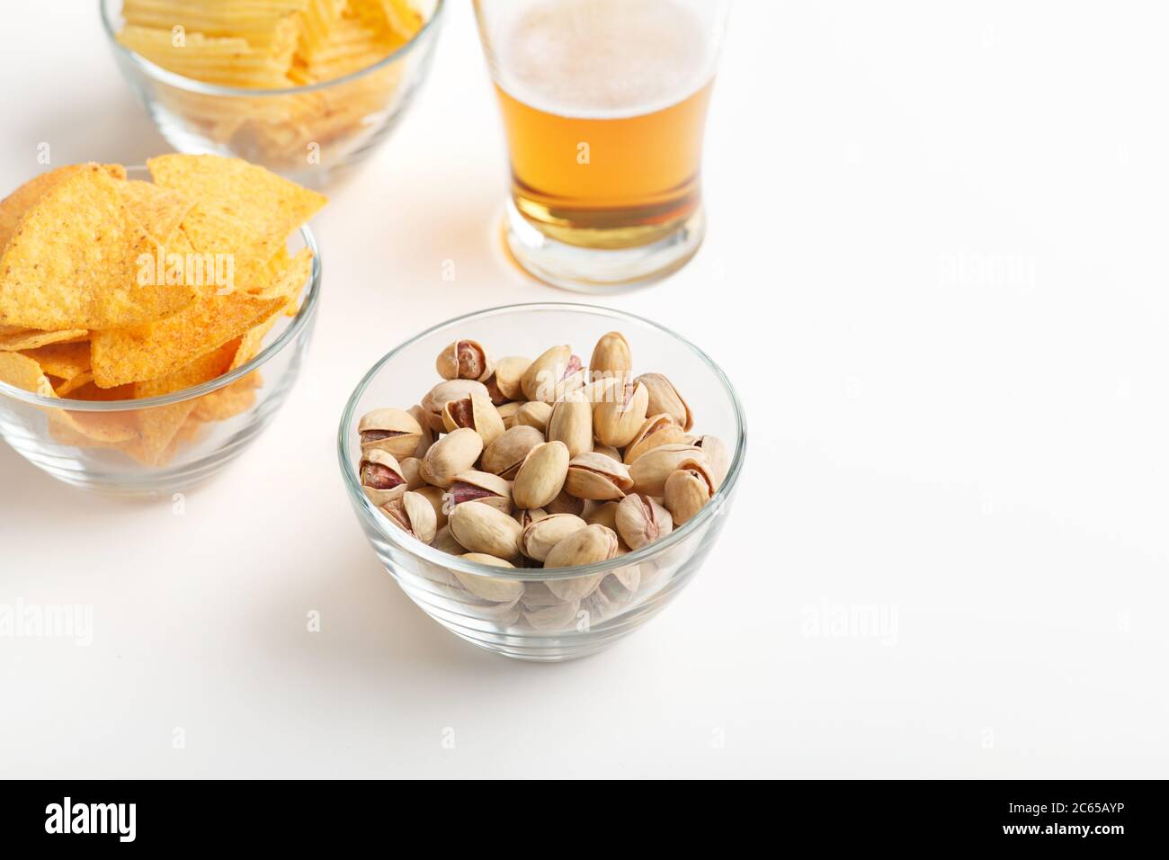 Spuntini croccanti per la birra. Nachos, pistacchi e patatine in lastre di vetro e birra chiara in vetro Foto Stock
