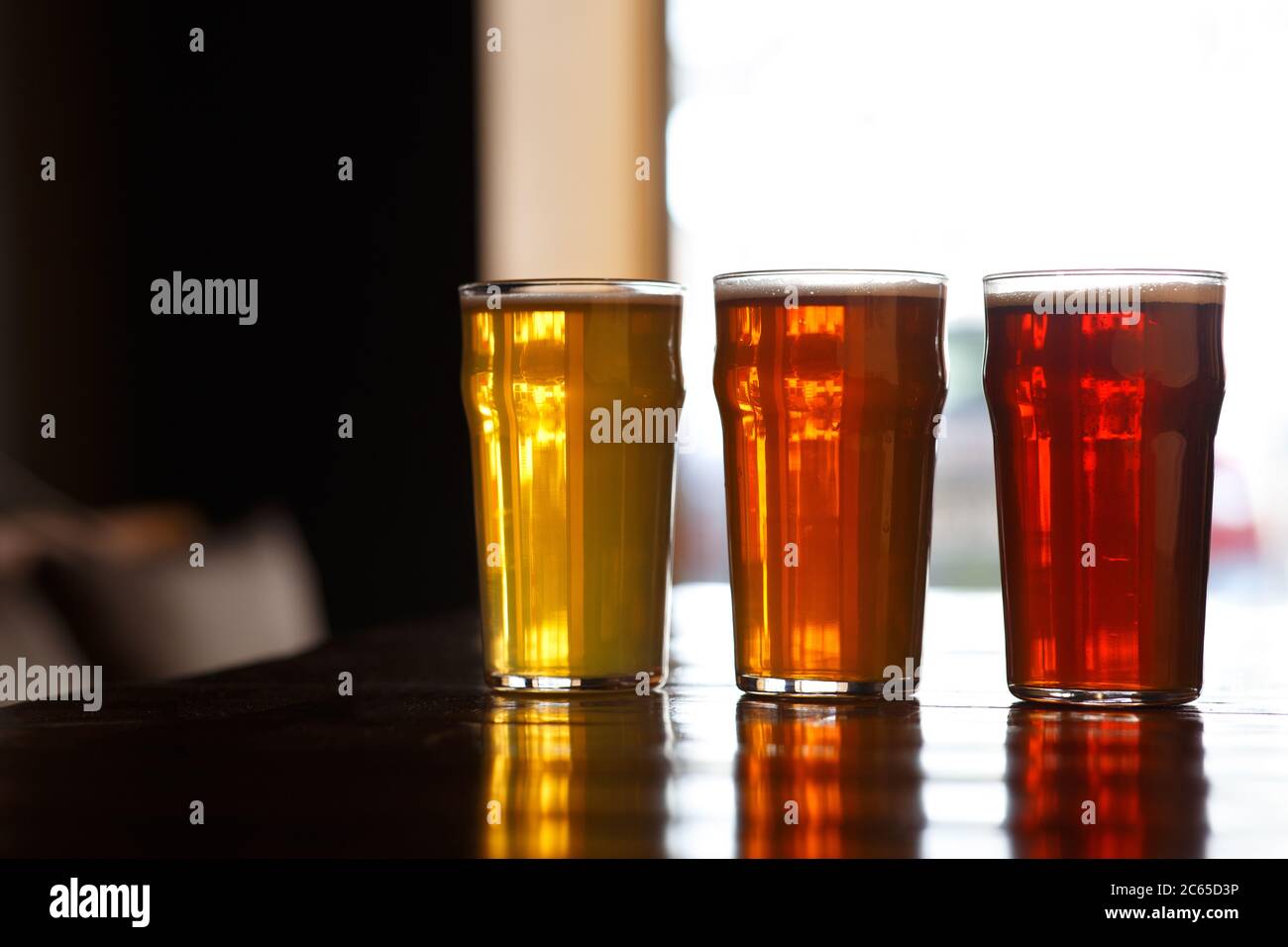 Lager, birra e orzo in bicchieri su tavolo su sfondo finestra Foto Stock