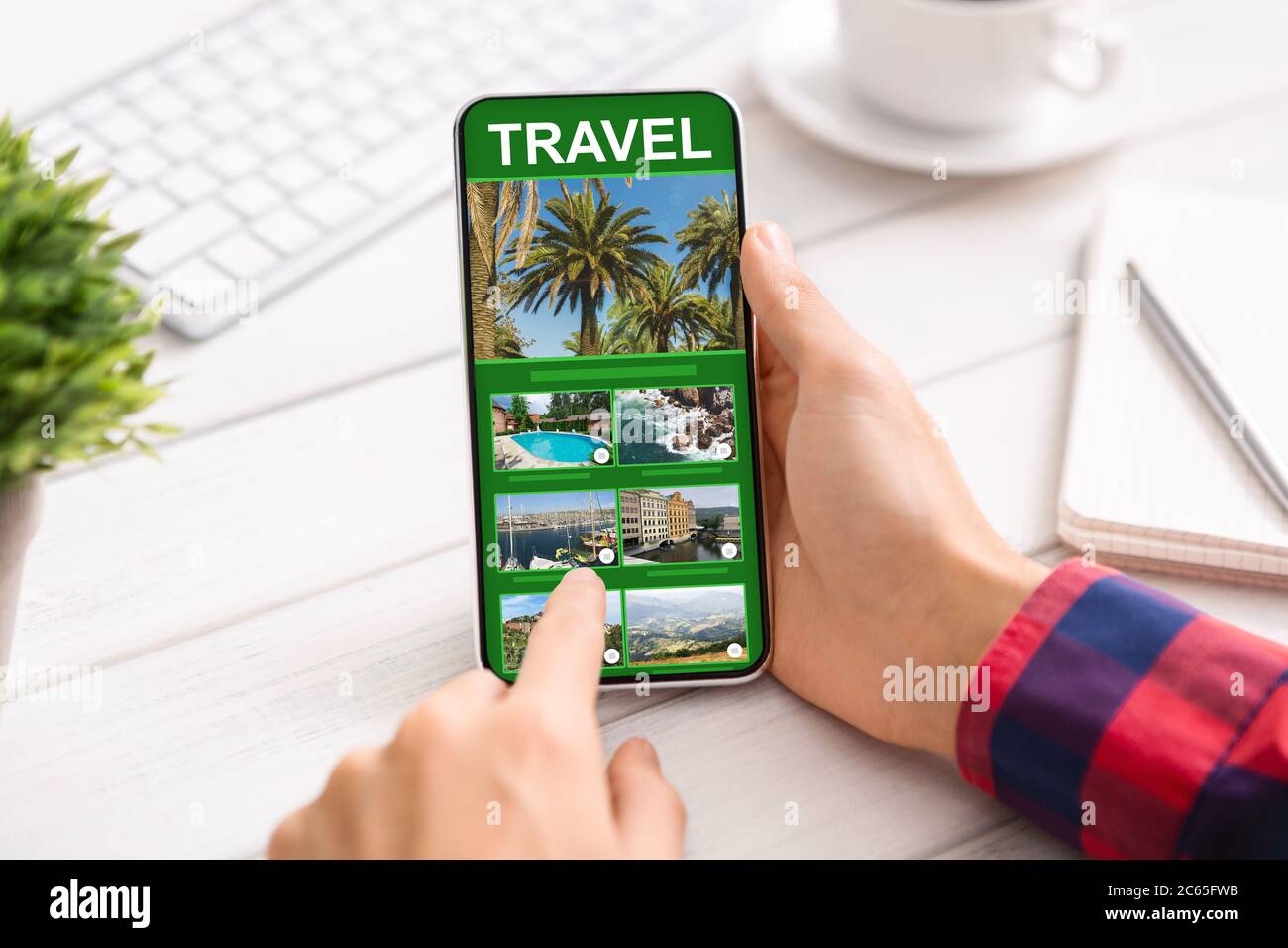 Uomo che usa lo smartphone con l'app Online Travel in Office, esplorando le destinazioni future Foto Stock