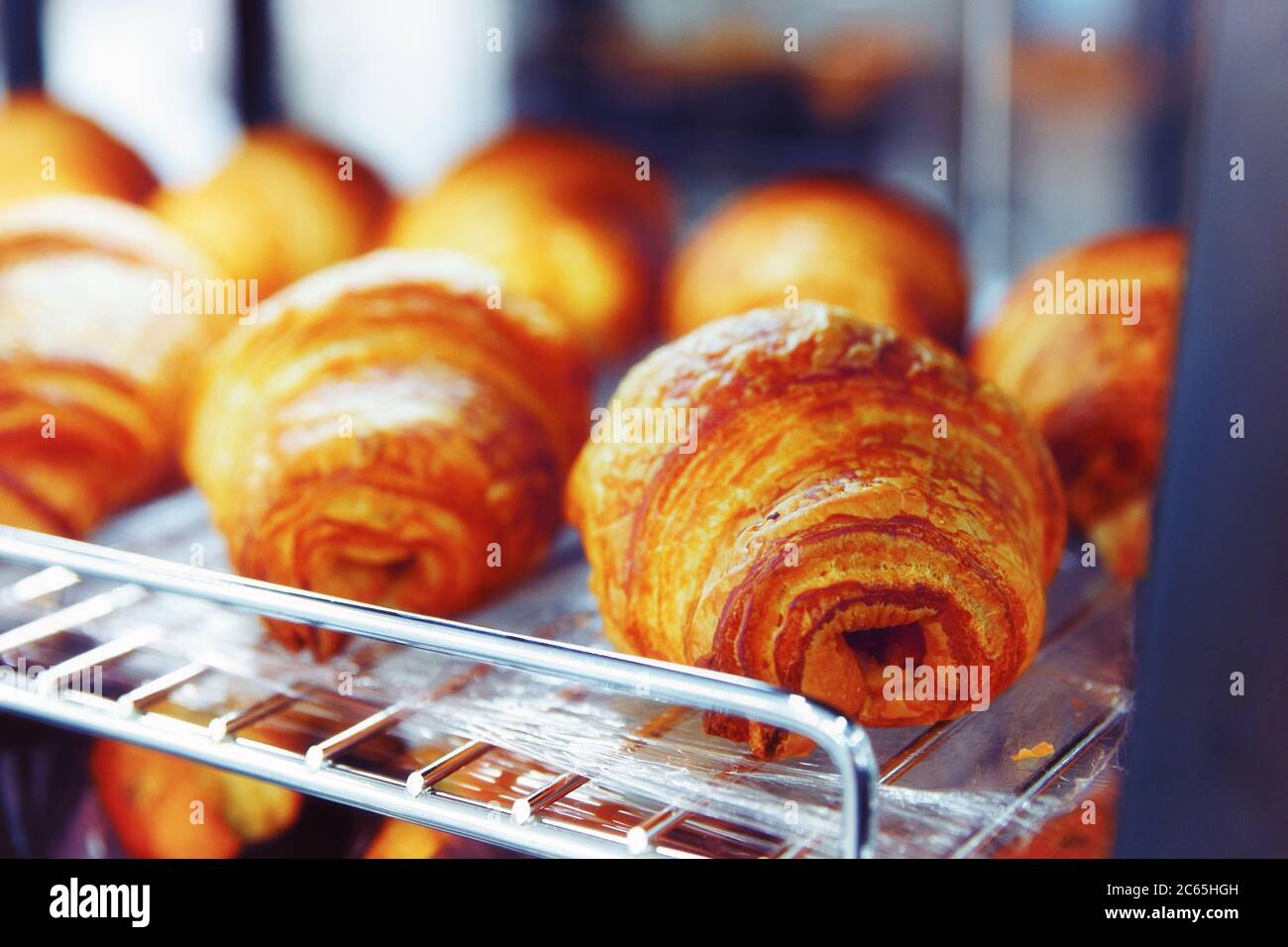 Croissant al forno su griglia metallica, primo piano, tonato Foto Stock