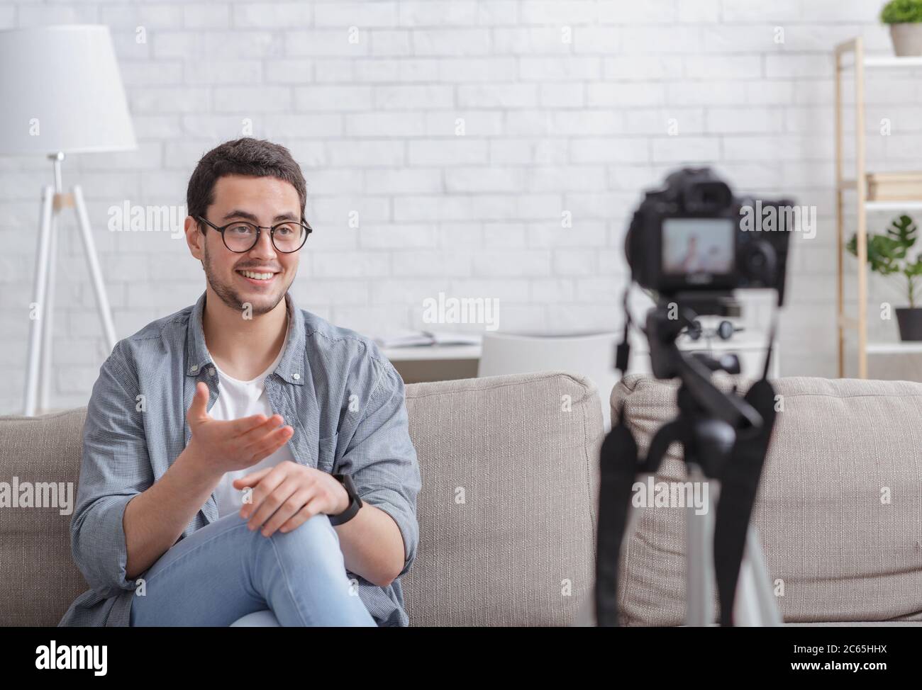 Blog a tema a casa. Guy che registra video sulla fotocamera Foto Stock