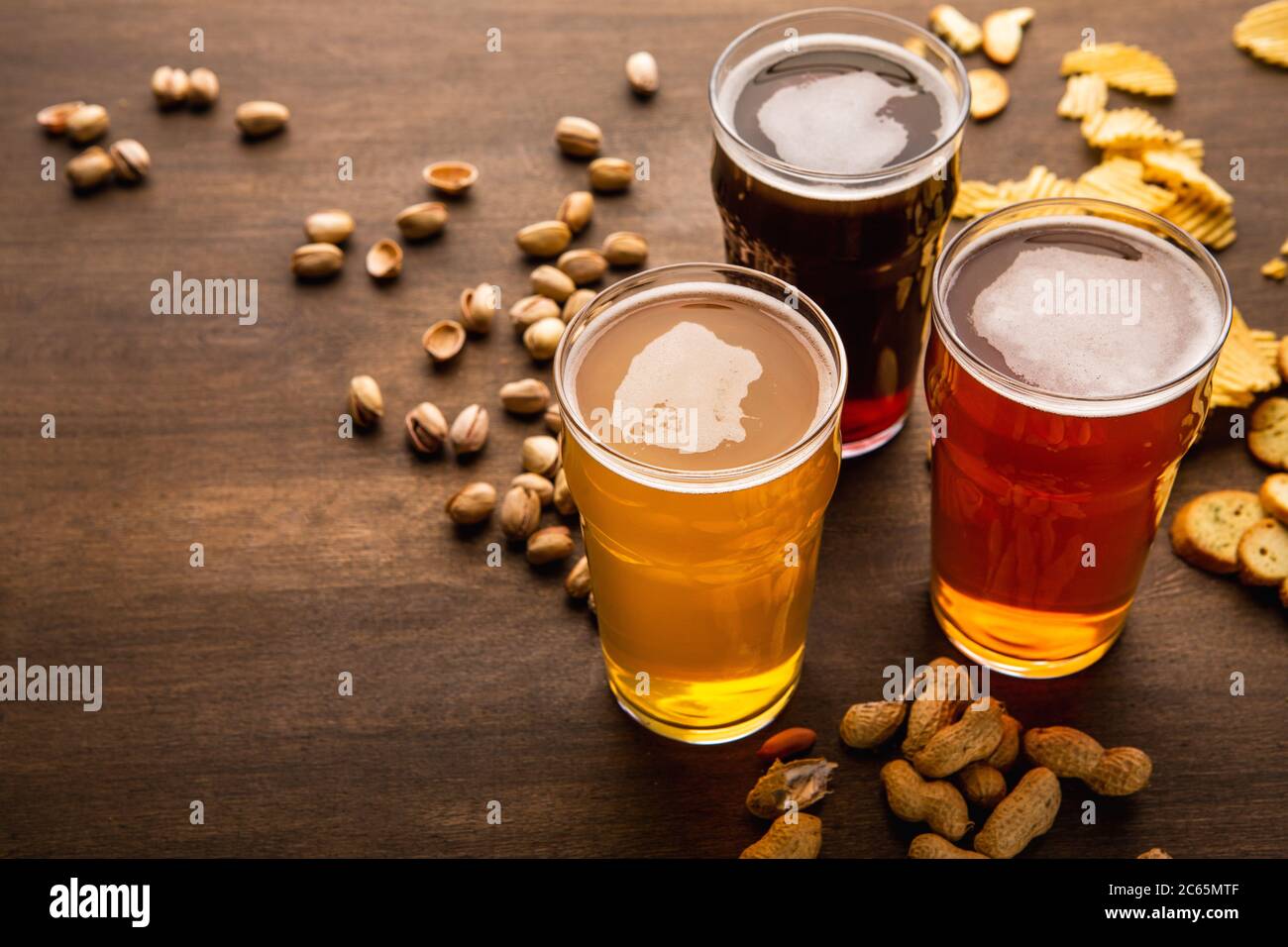 Birra artigianale per ogni cliente. Spuntini sparsi su un tavolo di legno marrone Foto Stock