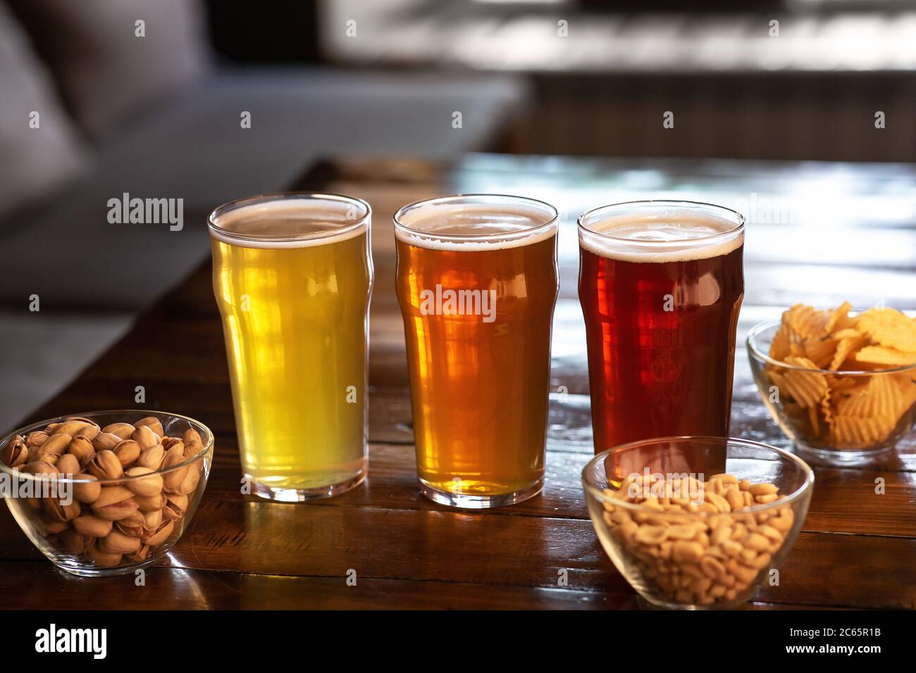 ALE, lager e birra in bicchieri. Pistacchi, noci e trucioli in lastre di vetro su tavolo Foto Stock