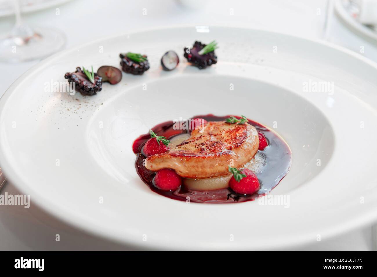 Foie gras con salsa al porto su piatto bianco, alta cucina, primo piano, tonato Foto Stock