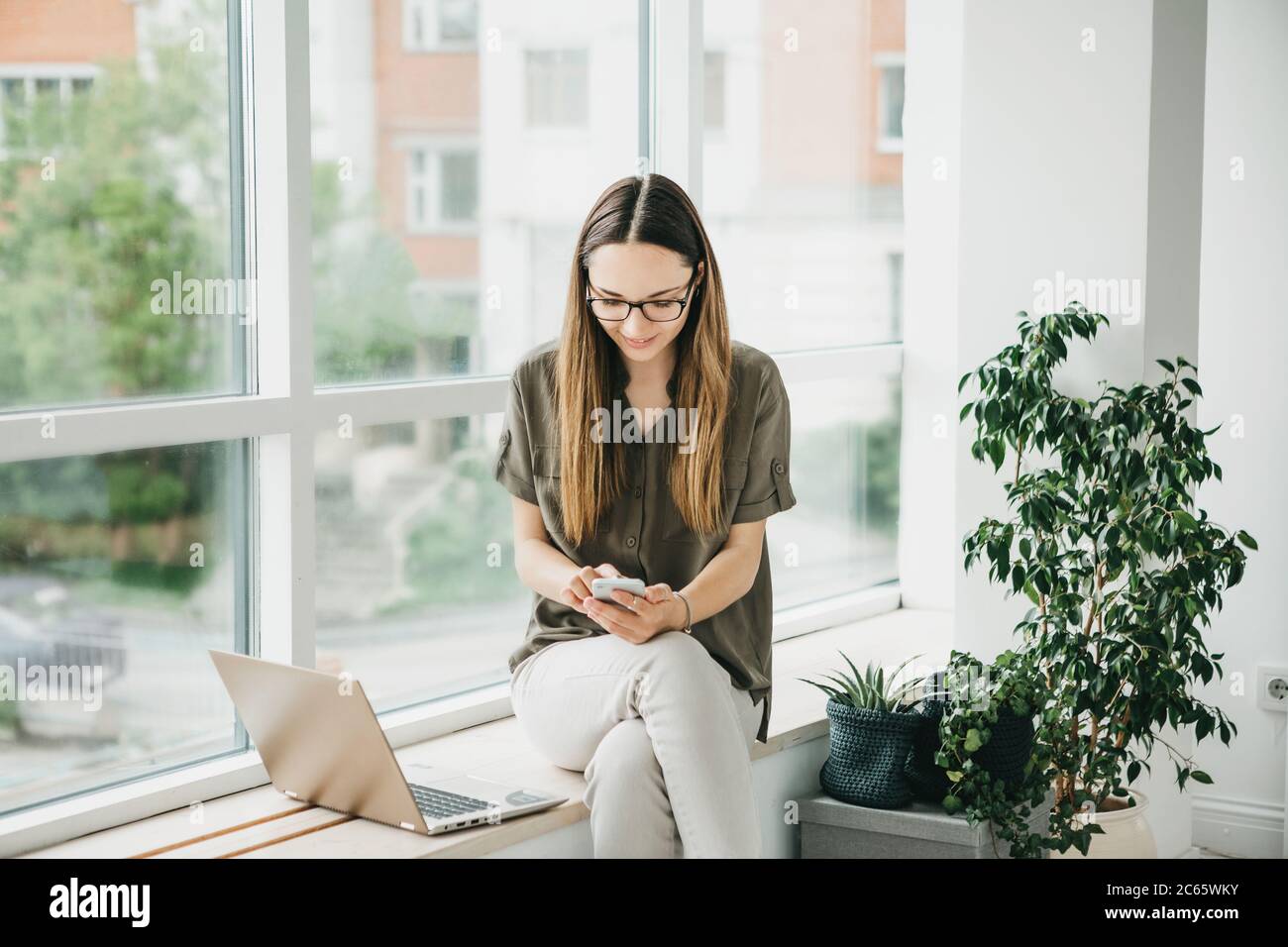 Giovane bella ragazza o studente usa un computer portatile e cellulare o telefono cellulare. Foto Stock