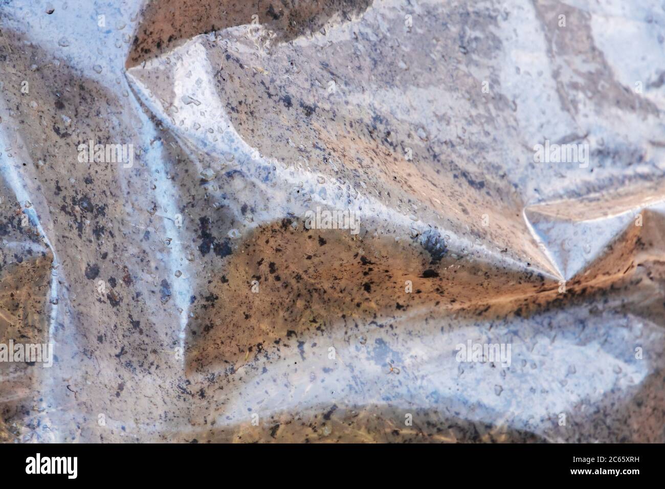 La pellicola sporca di polietilene giace sul terreno, l'illustrazione dell'effetto serra Foto Stock