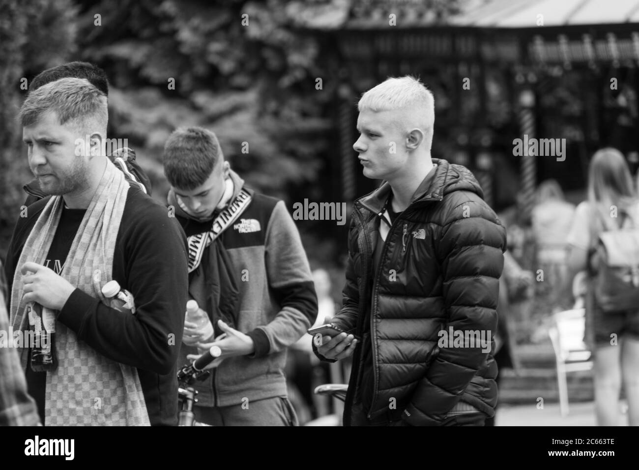 Giovane ragazzo biondo con i suoi amici in un parco pubblico, Harrogate, North Yorkshire, Inghilterra, Regno Unito. Foto Stock