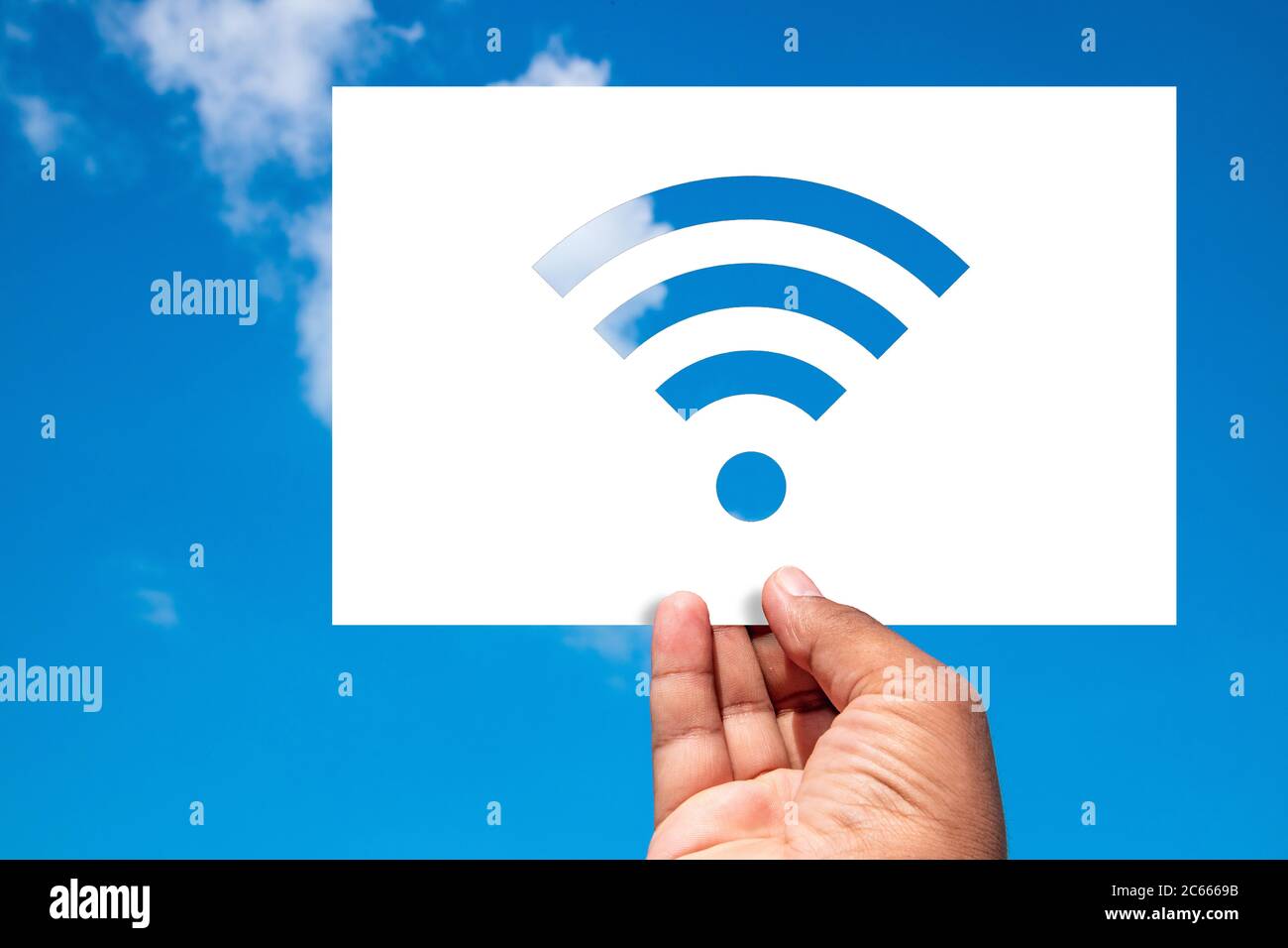 Concetto wireless. L'uomo tiene un foglio di carta con un ritaglio wireless a forma di Wi-Fi contro il cielo blu. Foto Stock