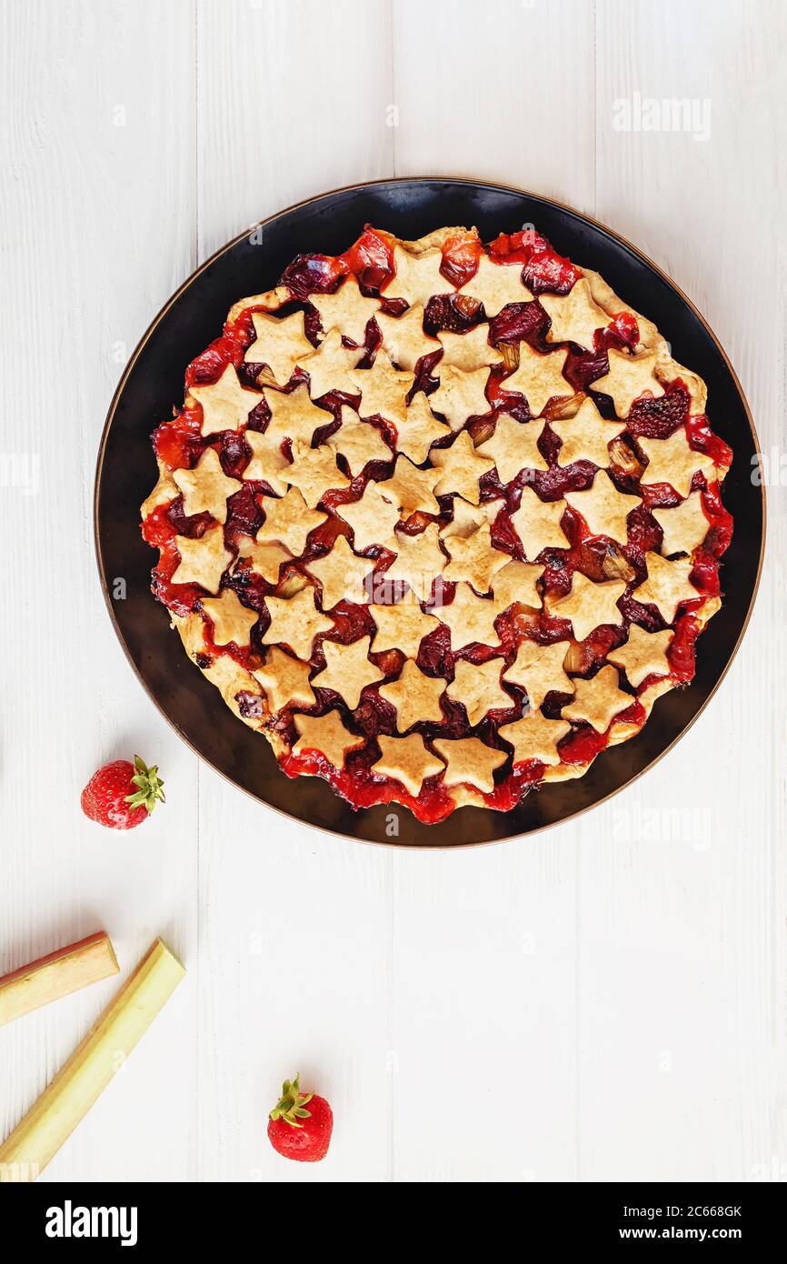 Torta di fragole e rabarbaro decorata con stelle su tavola bianca, vista dall'alto Foto Stock