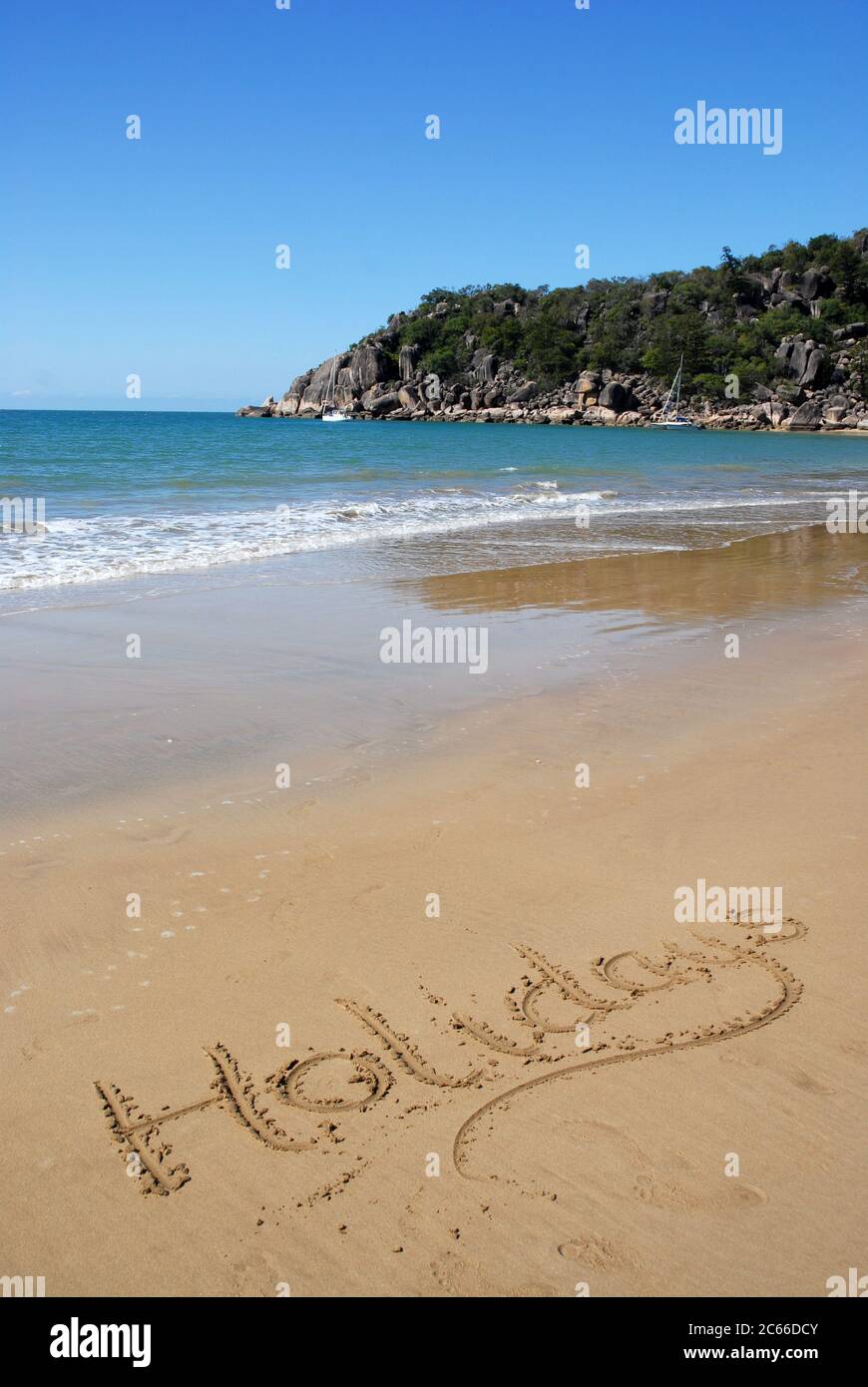 Idilliaca vista sulla spiaggia con la parola Vacanze scritte sulla sabbia, Radical Bay, Isola Nagnetic, Queensland, Australia Foto Stock