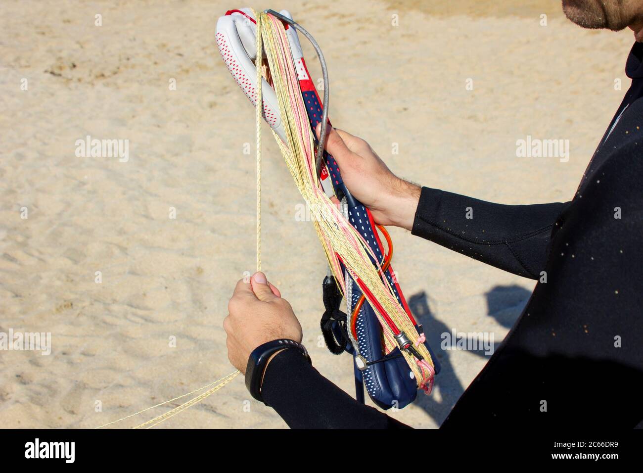 primo piano un uomo lancette rotolando un kite bar e linee sulla spiaggia dopo kitesurf. Attrezzatura per kitesurf per corsi di kite. Sport acquatici estremi. Lo selvaggio Foto Stock