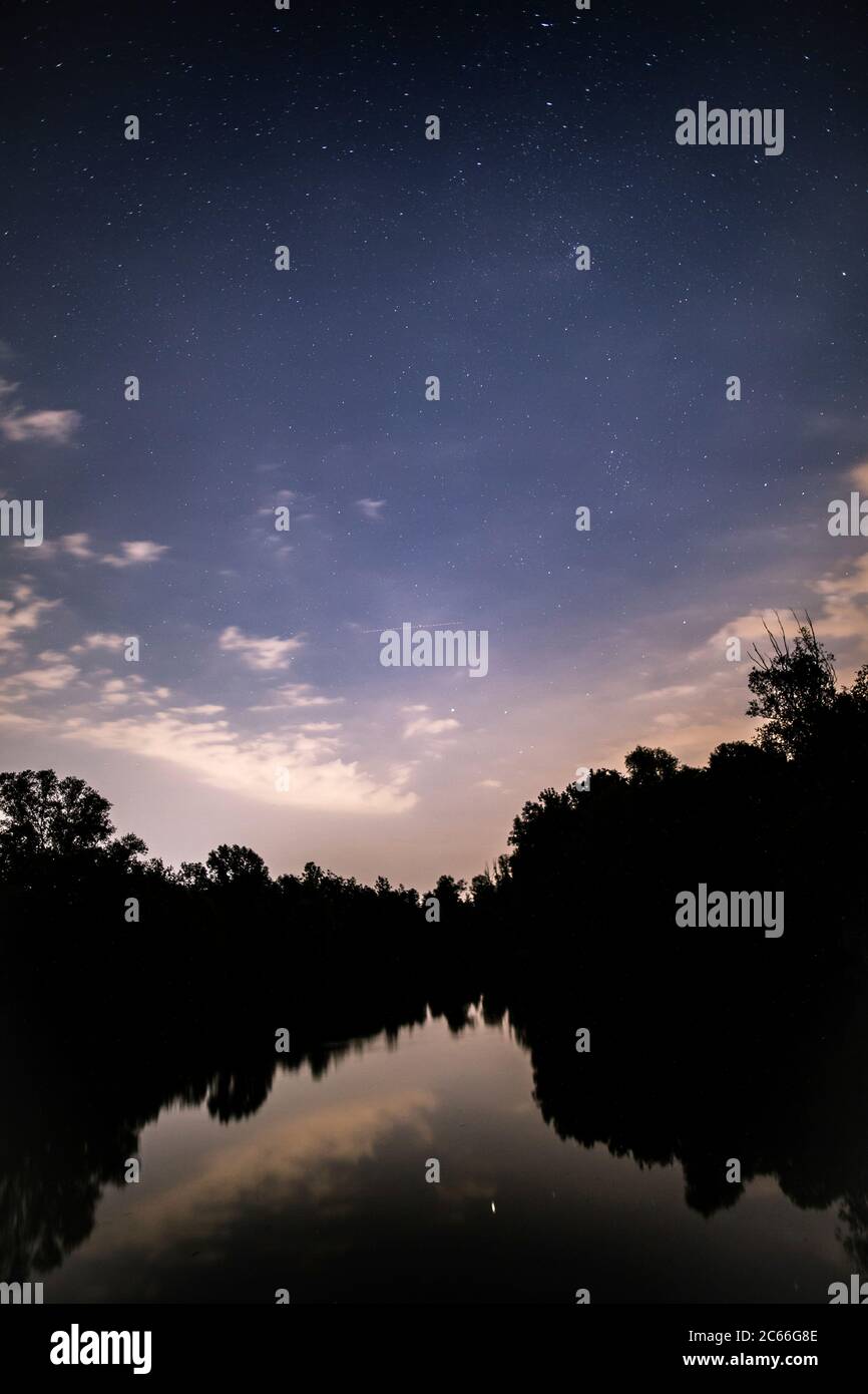 Cielo stellato con nuvole sopra l'acqua Foto Stock