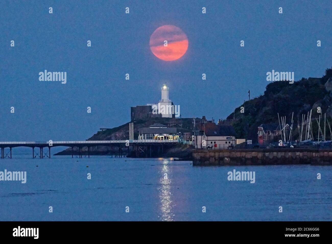 Una luna piena, conosciuta come Flower Moon, sorge sul faro di Mumbles vicino a Swansea, Galles, Regno Unito. Giovedì 07 maggio 2020 Foto Stock