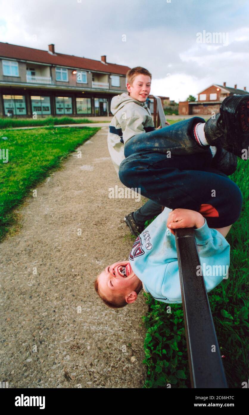 Ragazzi che giocano vicino a negozi di run down council estate; Bradford UK Foto Stock