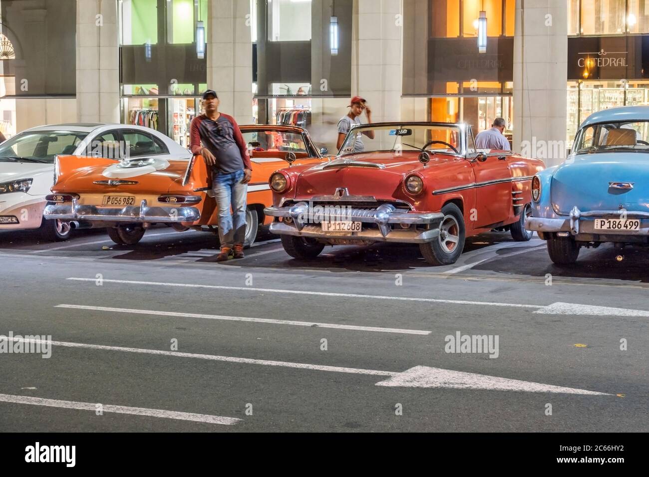 Cuba, l'Avana, scena notturna, auto d'epoca e autista in attesa per i clienti al Parque Central Foto Stock