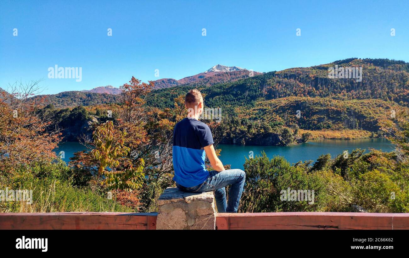 Persona seduta sulla pietra con vista sul lago Machónico, Argentina Foto Stock
