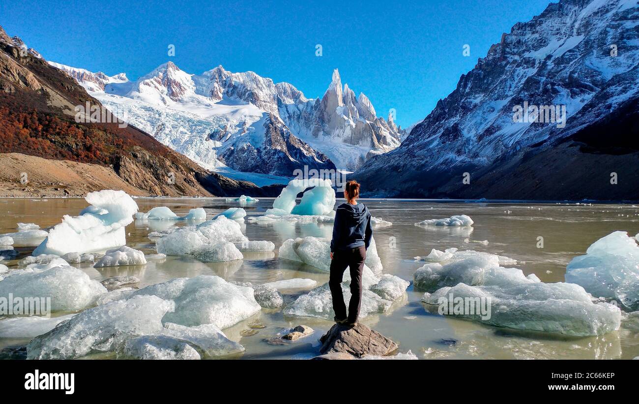 Persona in piedi sulla Laguna Cerro Torre con galleggianti di ghiaccio in acqua, circondato da montagne innevate, Argentina Foto Stock