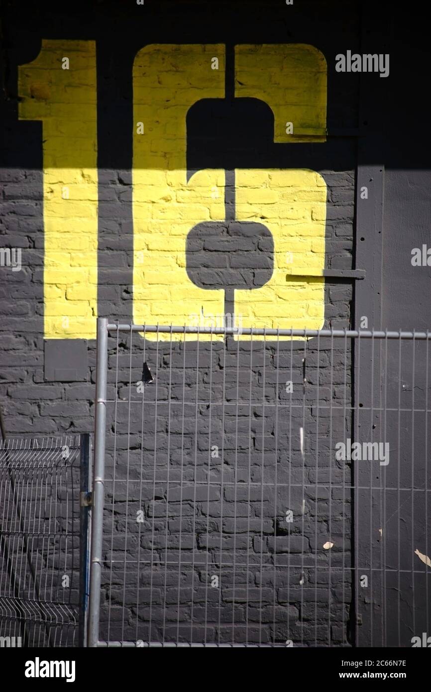 Un grande edificio giallo dipinto su un impressionante muro di mattoni dipinto di grigio scuro, Foto Stock