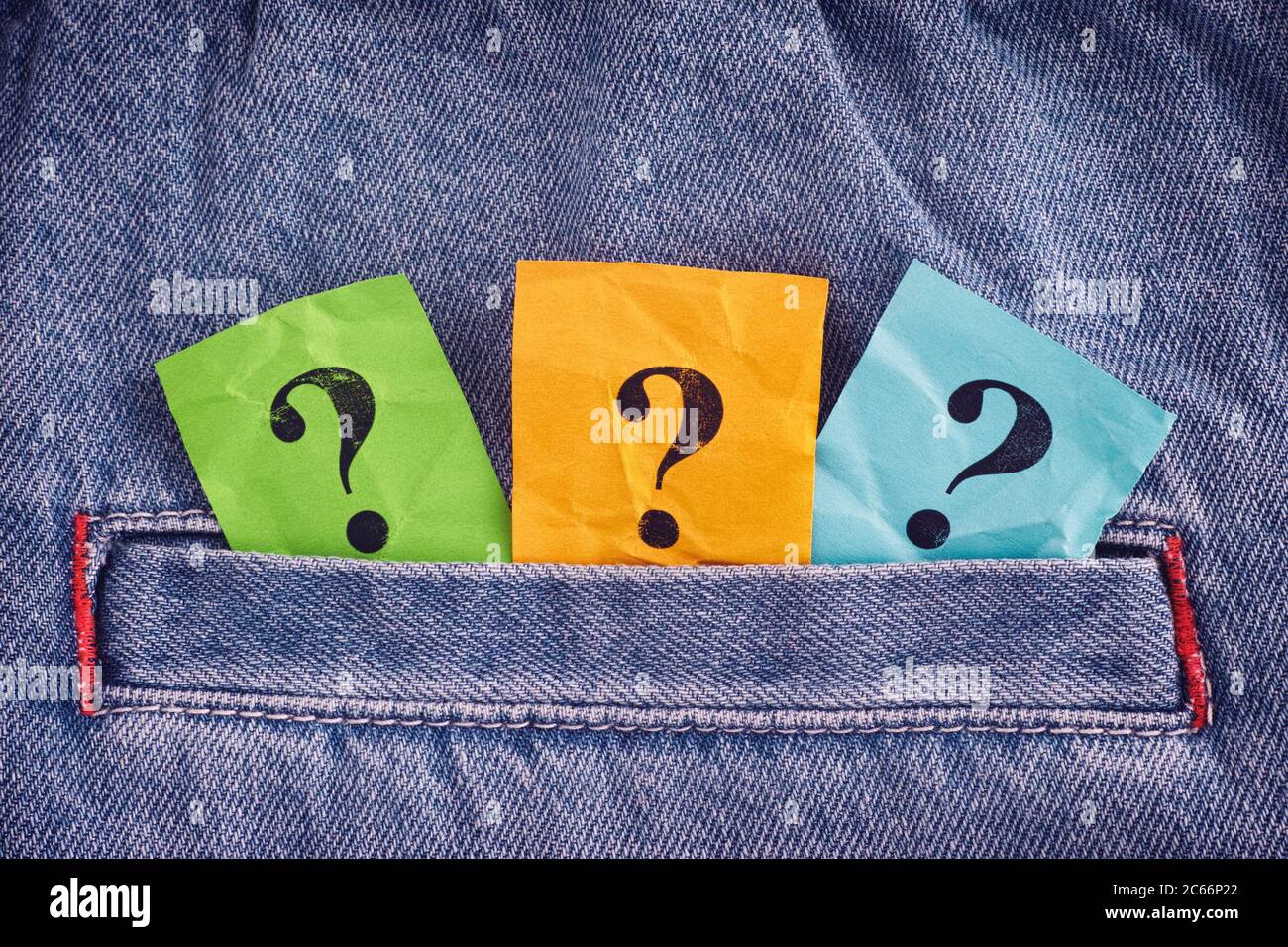 Punti interrogativi colorati che si stacca da una tasca di jeans. Primo piano. Foto Stock