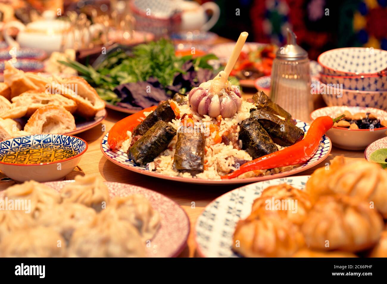 Tavolo servito con piatti tradizionali uzbeki - pilaf, dolma, gnocchi, tondi Foto Stock