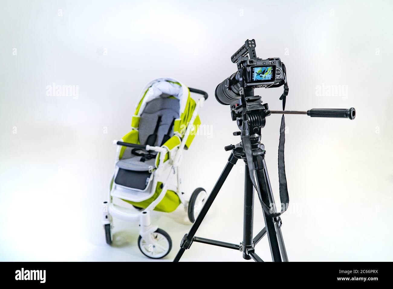 la fotocamera professionale è concentrata su un pram verde che si erge su uno sfondo bianco della stanza. Foto Stock