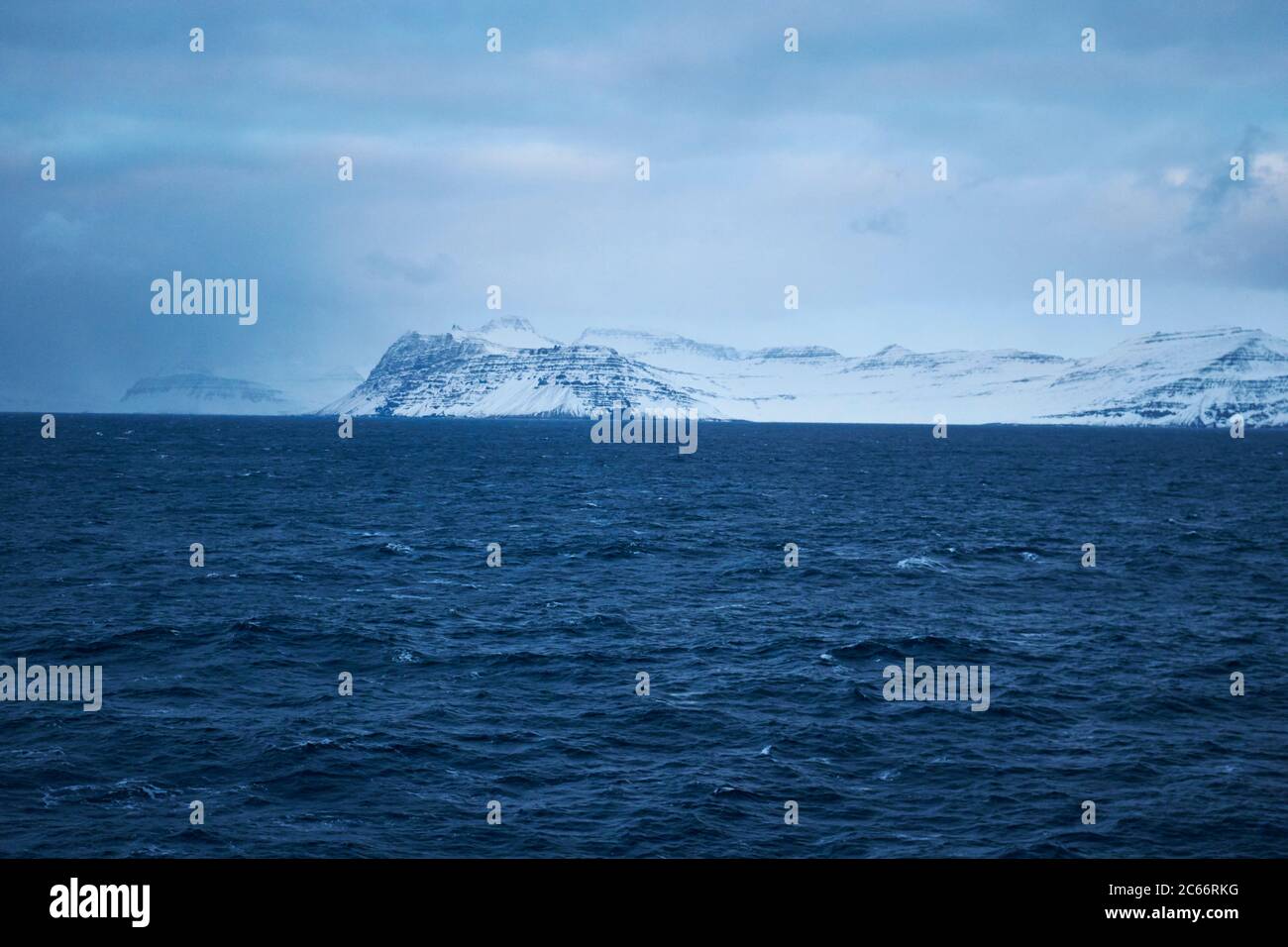 Islanda, catena montuosa in lontananza, cielo nuvoloso e acqua blu Foto Stock