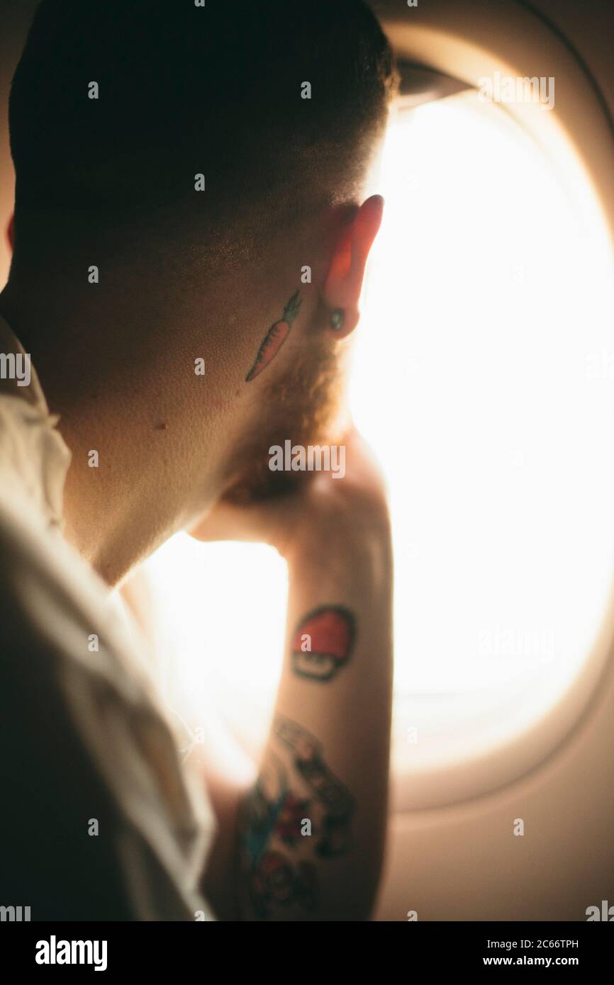 giovane uomo che guarda fuori la finestra di un aereo Foto Stock