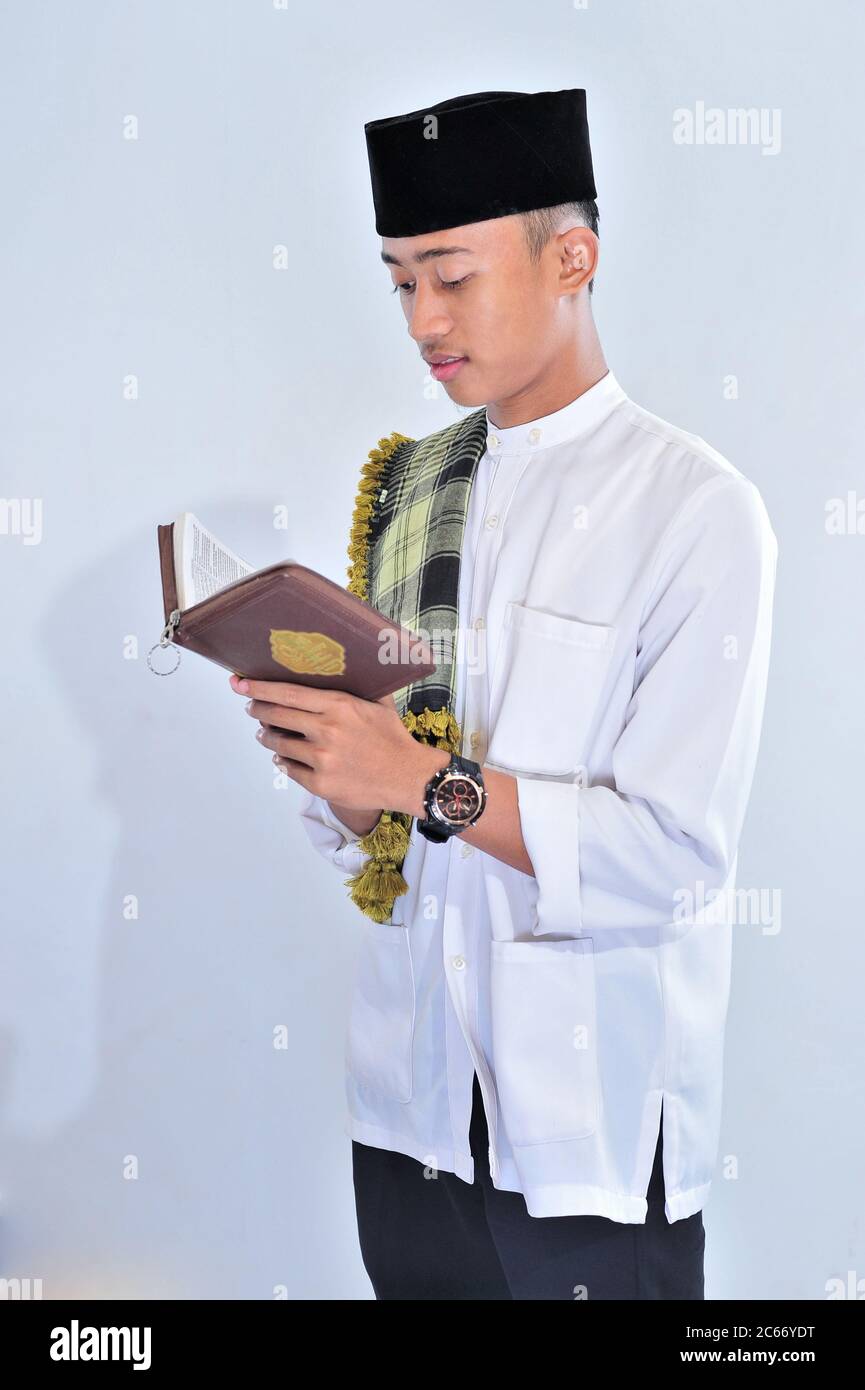 Ritratto di bel giovane musulmano piace leggere (tilawat ul quran) un santo Corano in Ramadan su sfondo bianco Foto Stock