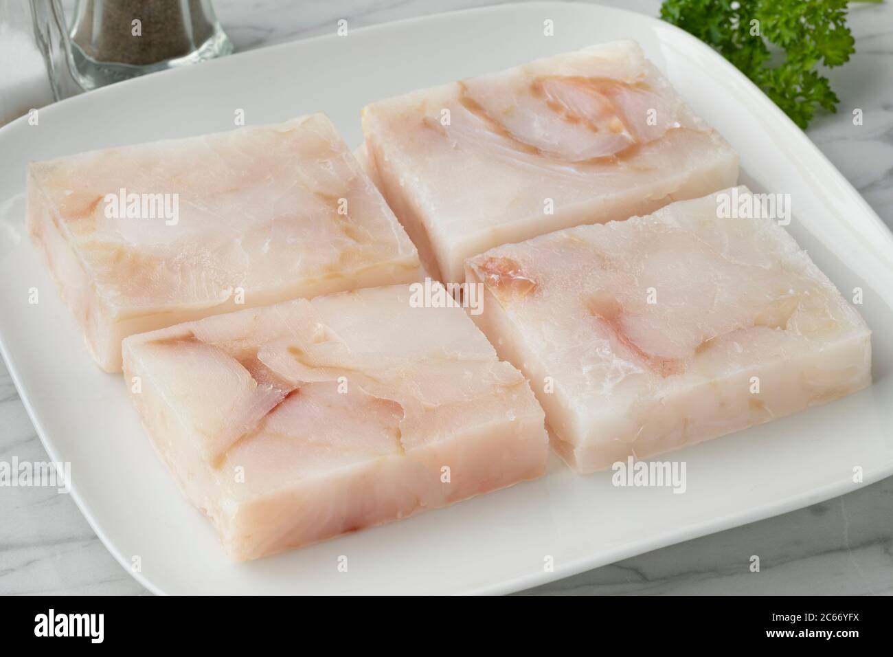Piatto con filetti di pesce di merluzzo surgelati per scongelare come ingrediente per cucinare Foto Stock