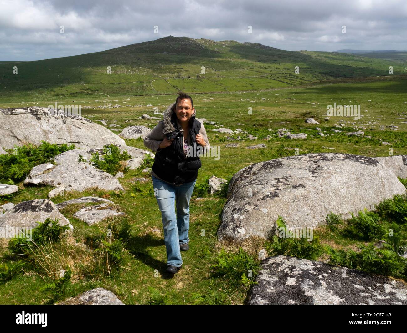 Donna che cammina su Bodmin Moor, con Brown Willy Tor sullo sfondo, Cornovaglia, Regno Unito Foto Stock