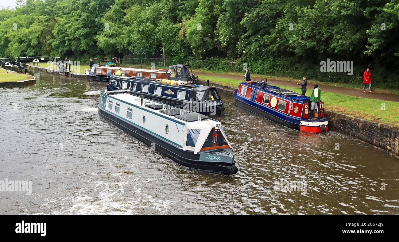 Quattro Narrow Boats che lavorano tra le chiuse 76 e 75 sul volo Wigan 12.6.2020, due che salono il volo e due giù. Un’estate piovosa a Wigan Foto Stock