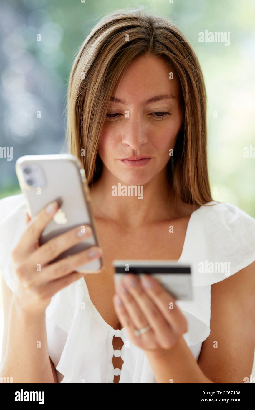 Donna che guarda il suo telefono e la sua carta di credito Foto Stock